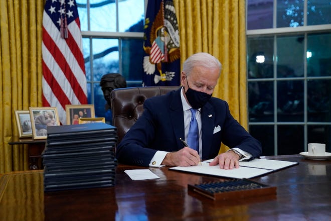 President Joe Biden signs his first executive orders in the Oval Office of the White House on Wednesday, Jan. 20, 2021, in Washington.