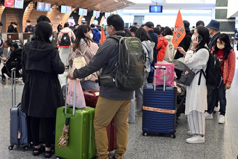 旅行社领队带着团员在桃园机场排队办理登机手续